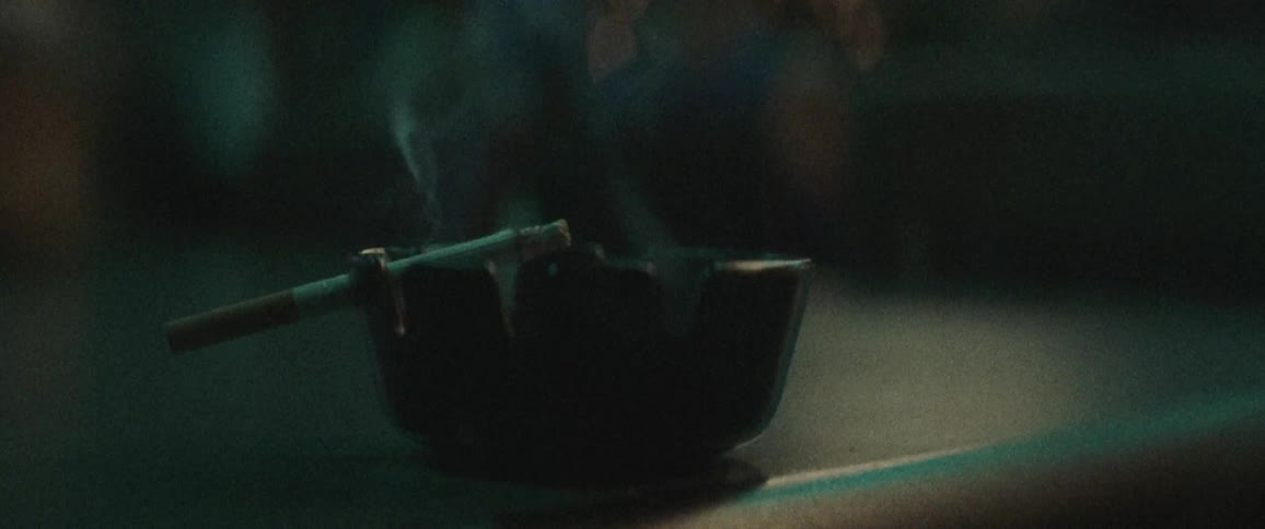 Cigarette smokes as it sits in ashtray on counter at bar