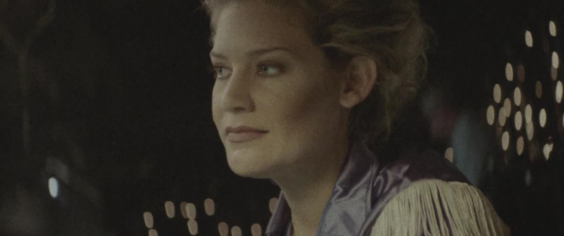 A woman in a country western shirt smiles in a bar