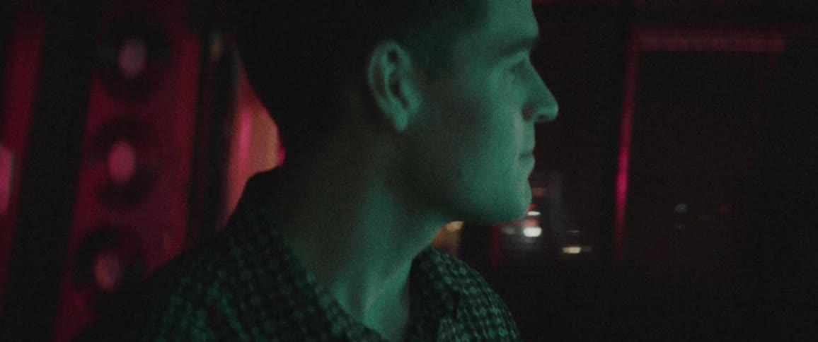A man in a bar walks past the door and windows looking around and smiling