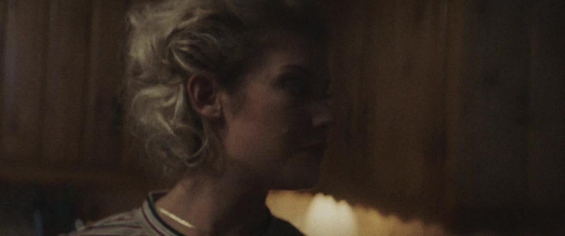 Blonde woman looks around in a room at night