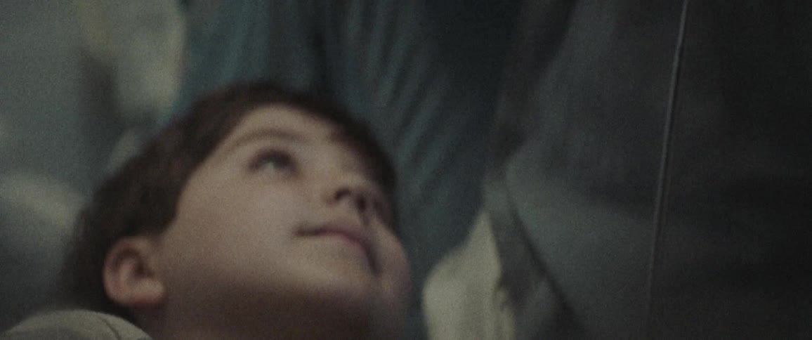 A child looks up smiling as he lays down