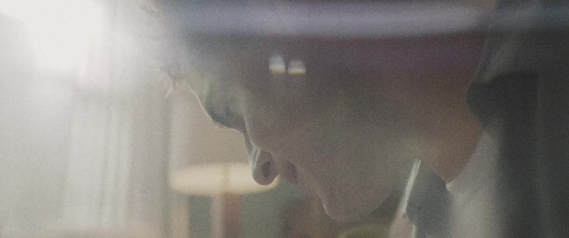 Man looks down and the sun shines through the window in a room