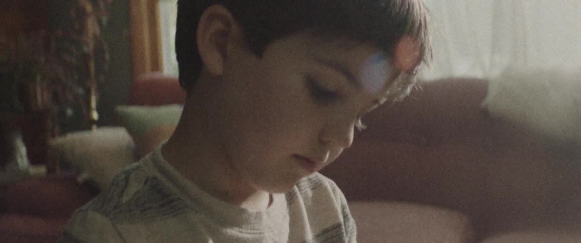 A young boy plays with something in a living room