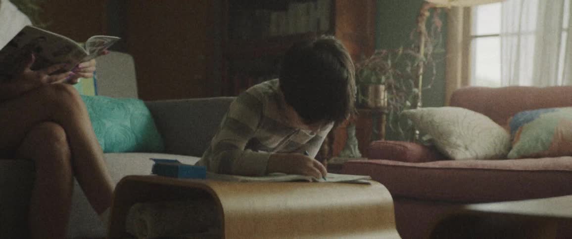 A young boy uses crayons to color in a coloring book in the family living room