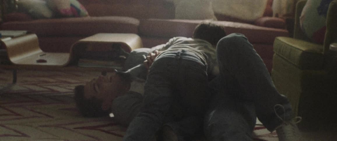 Man and boy wrestle on the living room floor