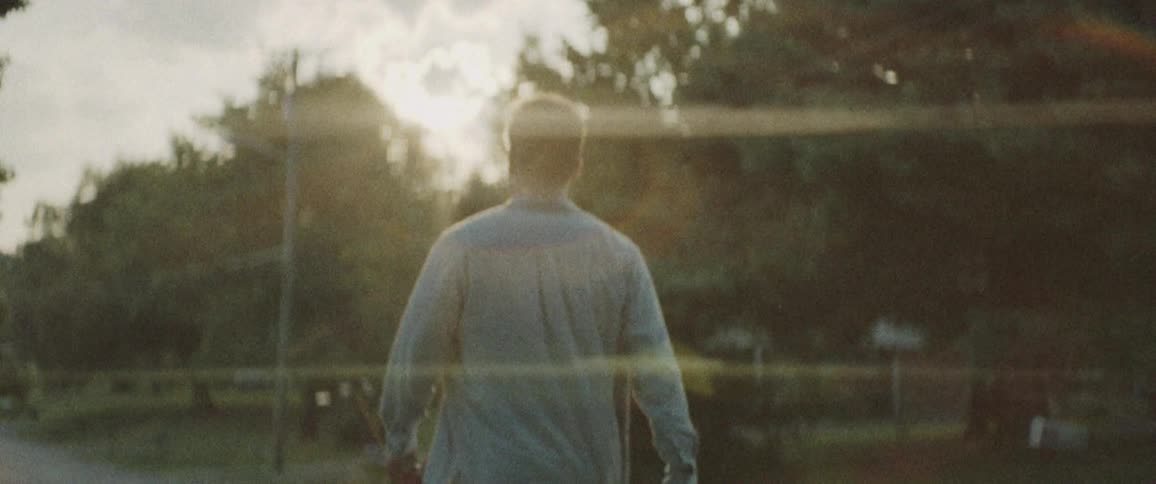 Man holding a rose walks on the road when the sun goes down