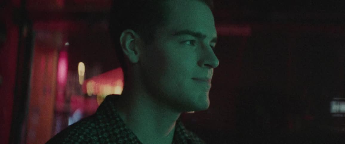 A man smiles while walking in a music store at night