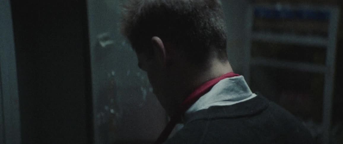 A young man opens a locker and puts on his work apron