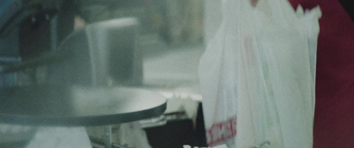 A cashier bags groceries and hands it to a customer