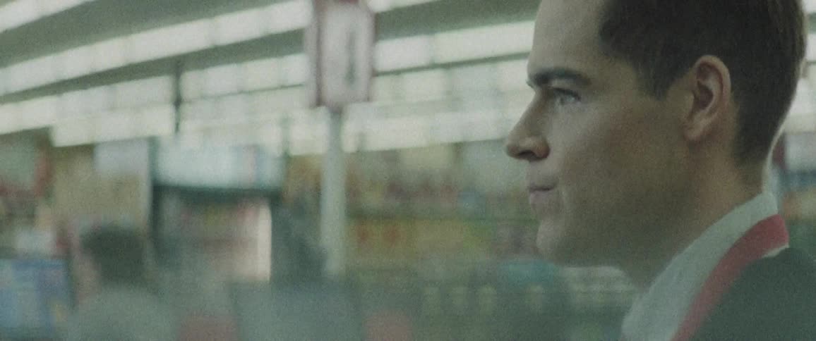 A young man stands in a store as he checks customers out