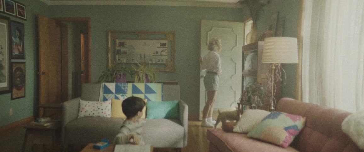 A boy is coloring in living room when his mother goes to answer the front door