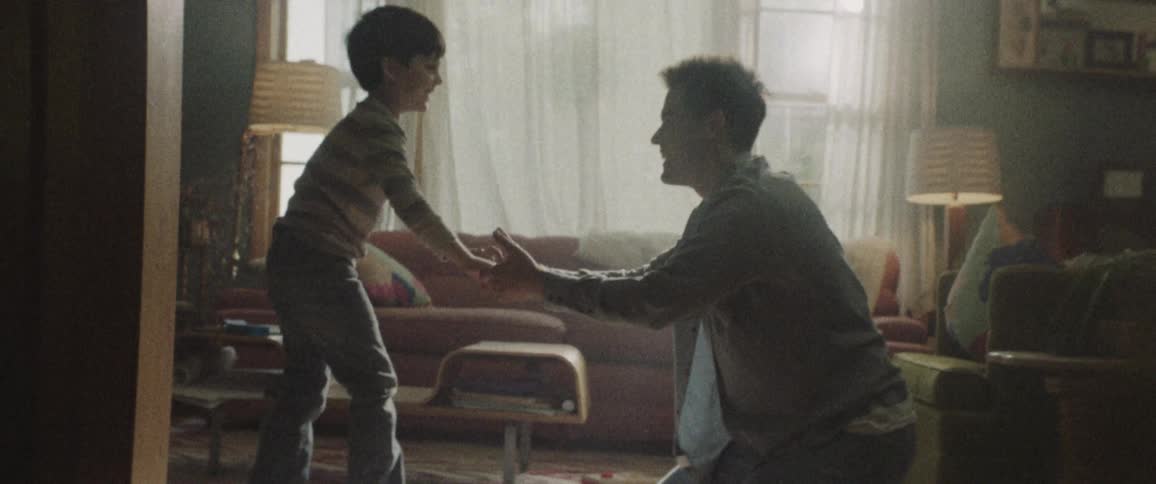 A man is playing with his son in the living room