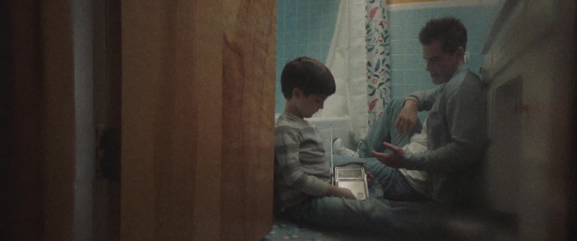 A child sits on the floor with his dad looking at pictures