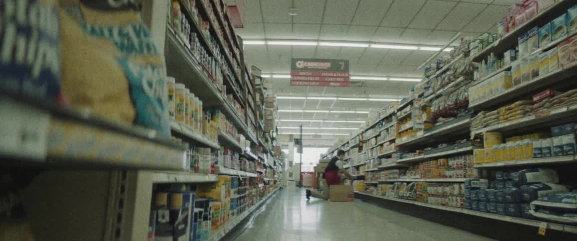 A grocery store employee stocks shelves with groceries