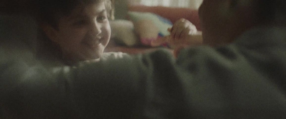 A boy roughhousing with a man in a living room