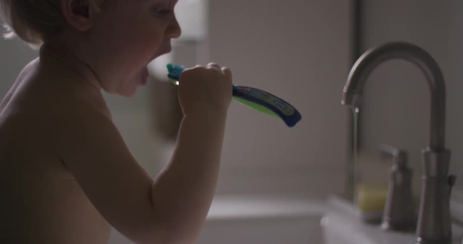 A baby sitting next to a faucet