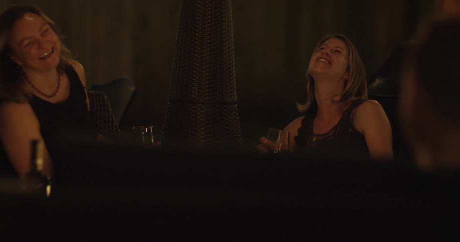 Women sitting around a fire chatting, laughing and holding glasses of wine