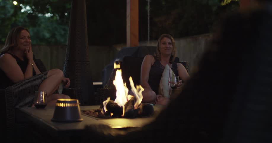 Two women laughing and talking in front of a fire