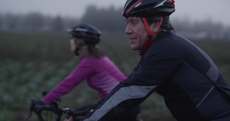 A man and woman bicycle in a rural area
