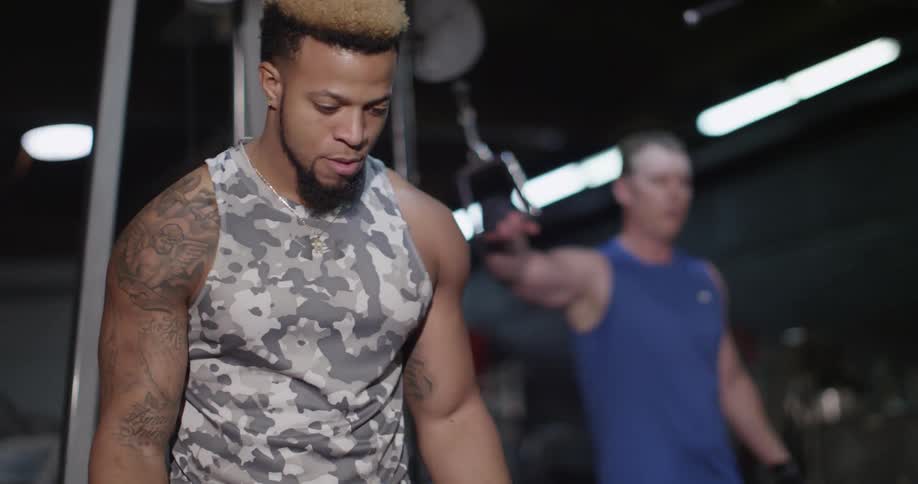 A man lifting weights being spotted in a gym