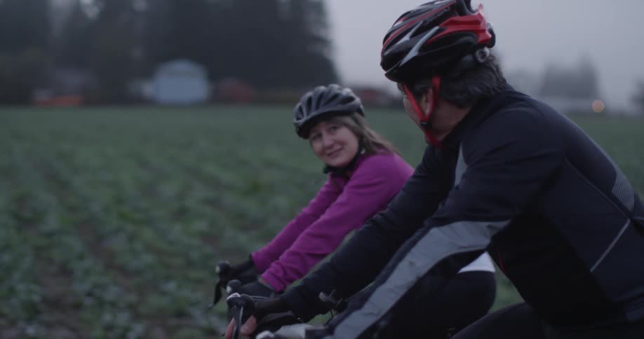 Couple riding bikes next to a field