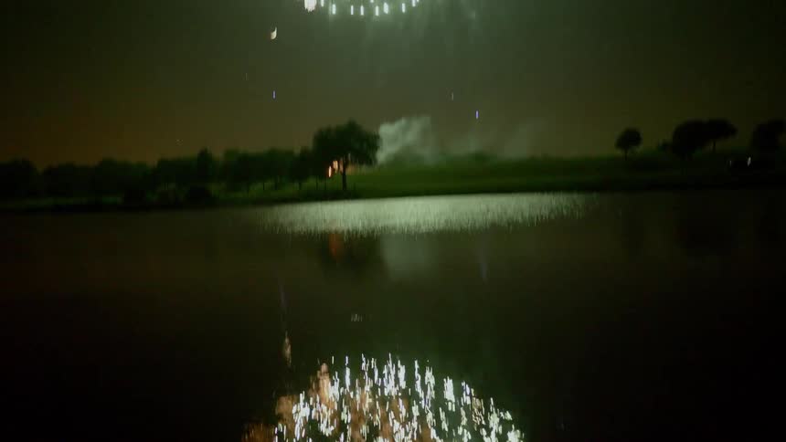 Fireworks shoot off in the sky and the reflection is seen in the water