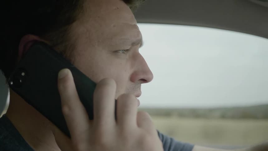 Man drives car and talks on the phone in the car