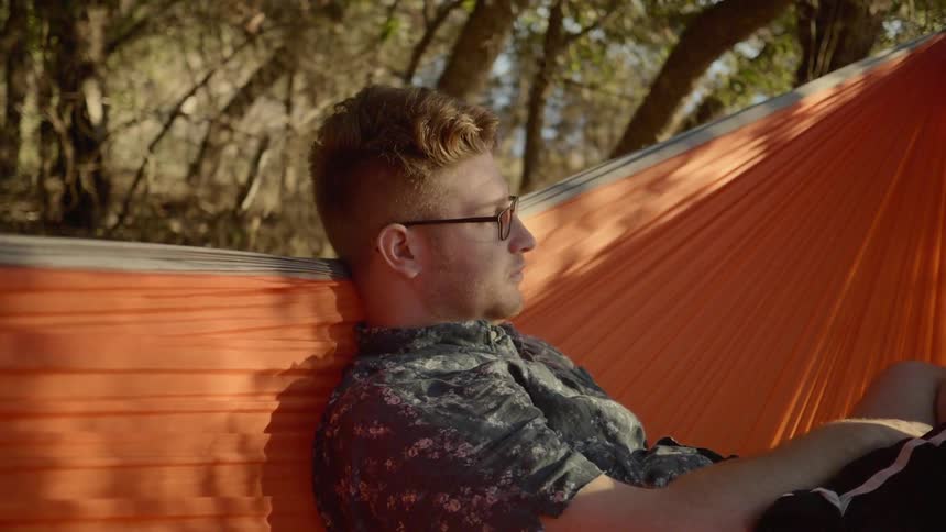 A man is sitting in an orange hammock