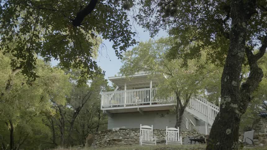 Chairs are placed outdoors near a tree in front of a home