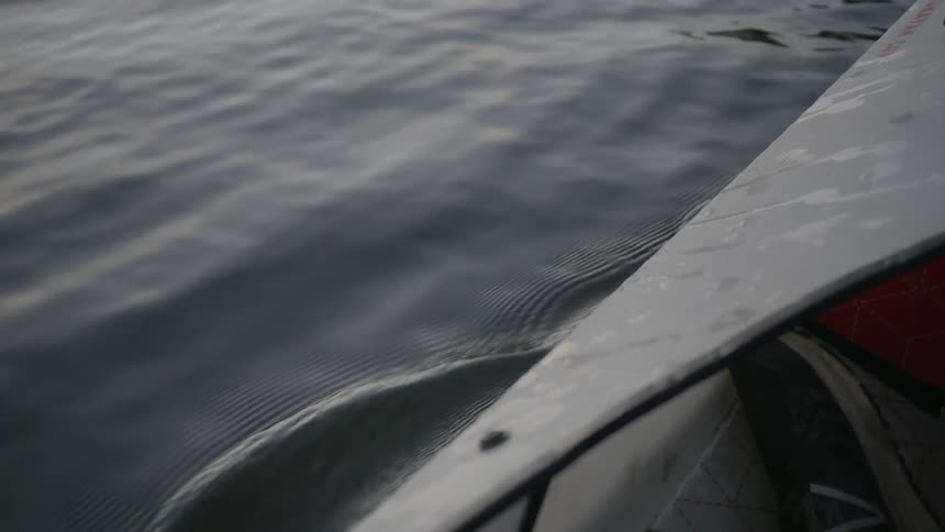 Canoe cuts through water causing wake and ripples