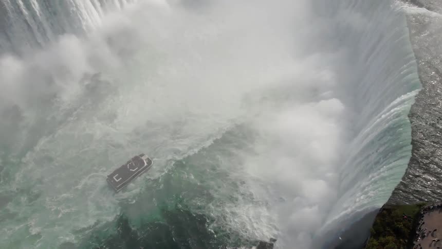The boat is getting close to the mist near the waterfall