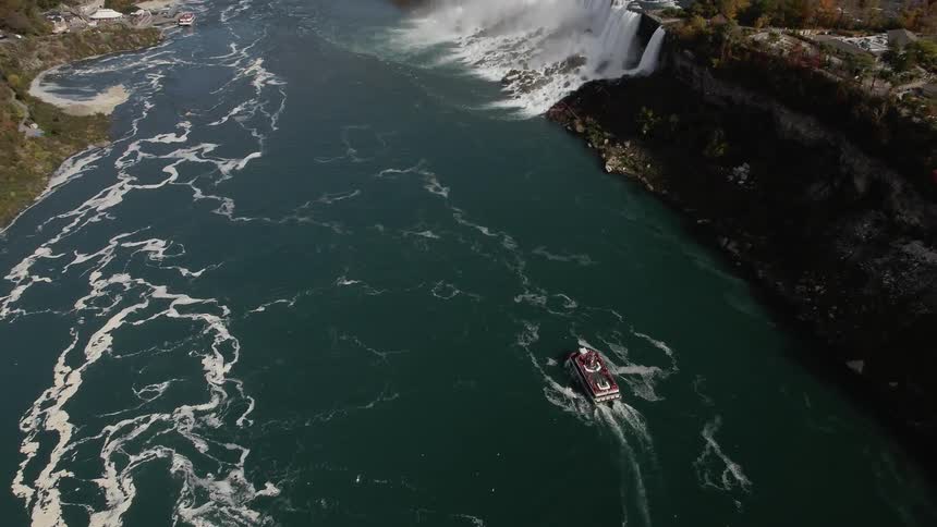 Birds eye view of a boat in a river with a water fall ahead