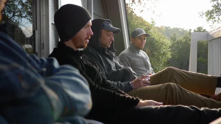 A group of men sitting on the porch of house during the day