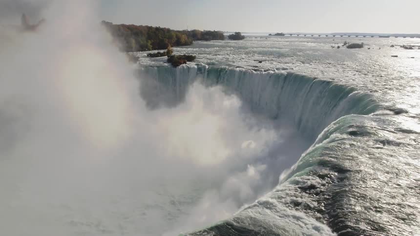 Water flows over the falls under a blue sky