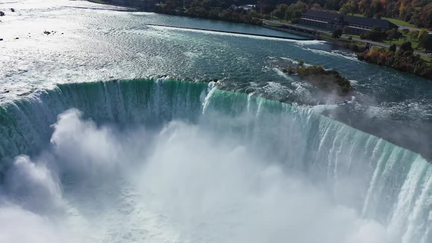 The large waterfall is giving off mist as it falls