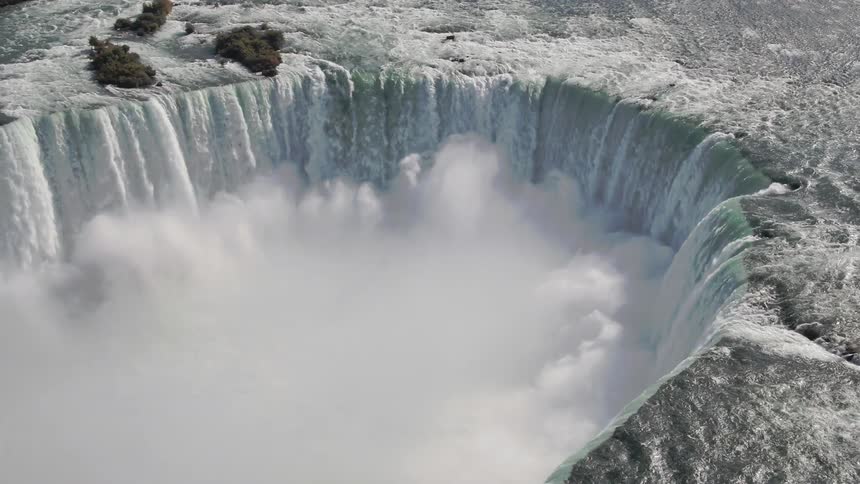 Water flows down massive horseshoe shaped falls during the day