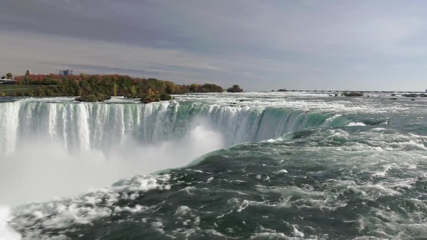 A fast moving and turbulent river feeds into a forceful waterfall