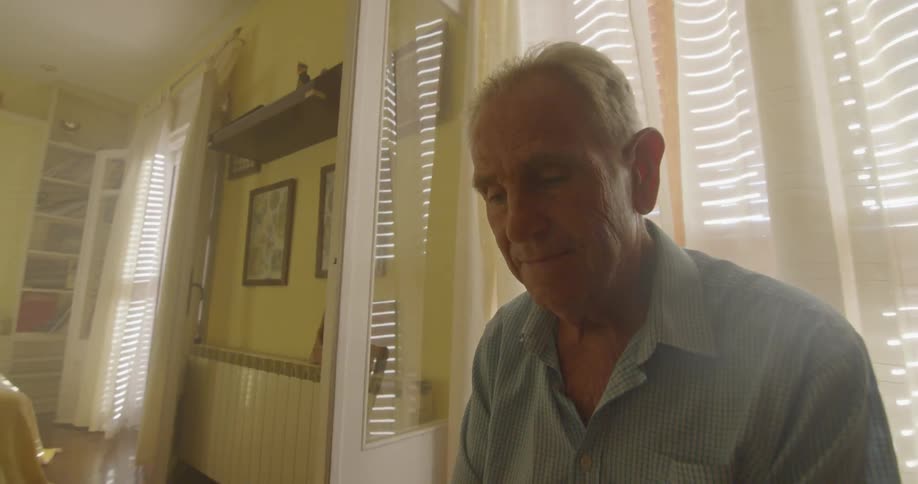 Old man sitting on the chair looks at the picture in a room