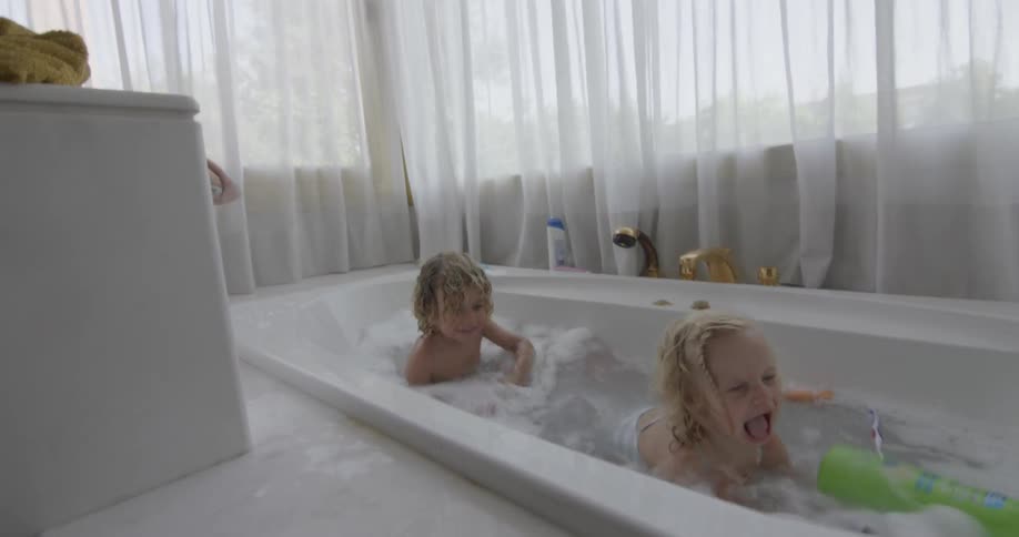 A boy and girl playing at the bathtub