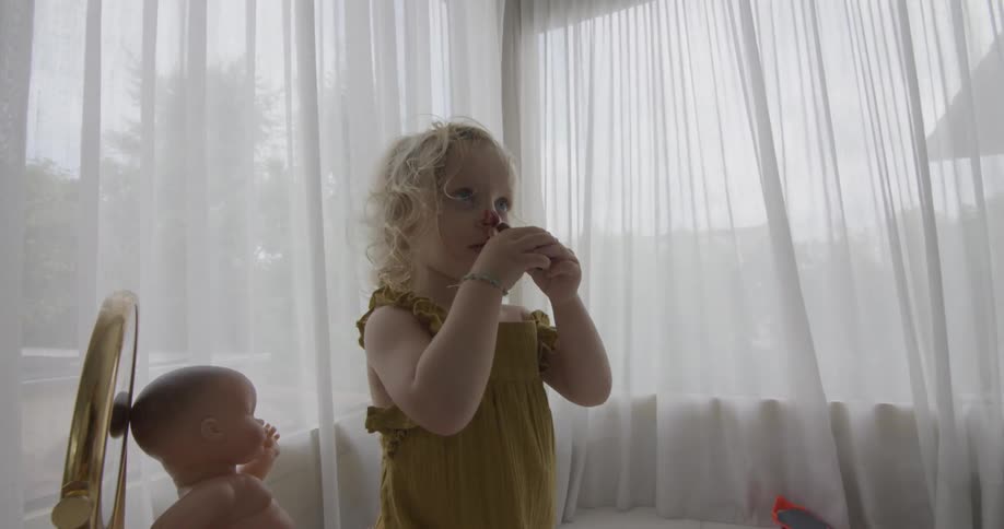 A little girl drawing on her nose with lipstick