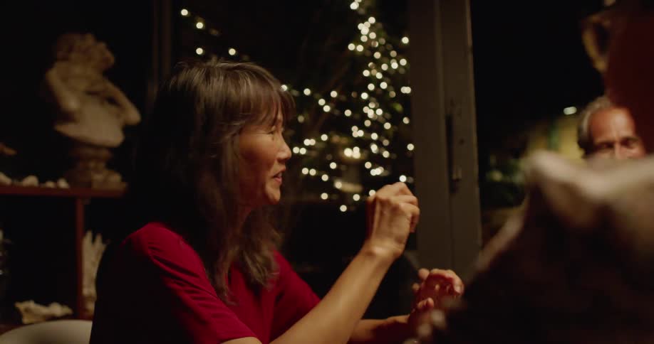 Two men and a woman sitting at the dinner table talking and laughing