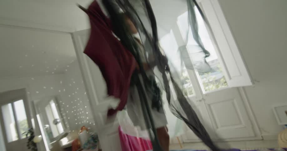 A child jumping on a bed holding a fabric covered umbrella