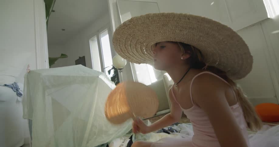 A portrait of a woman with a large hat on a white room