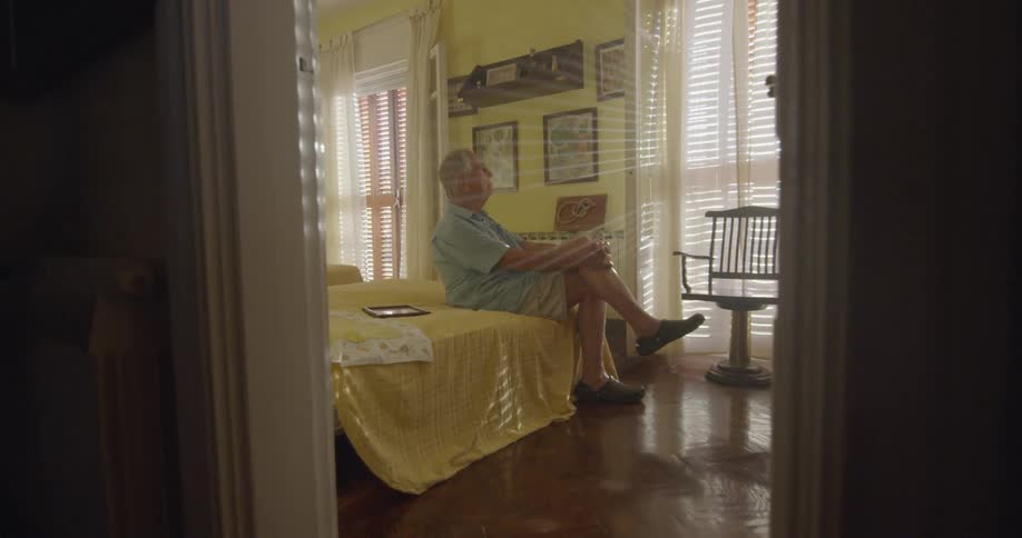 An elderly man sit on the bed