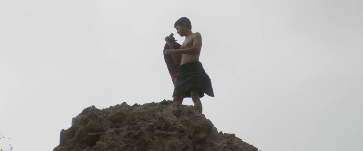 A young boy climbs to the top of a cliff