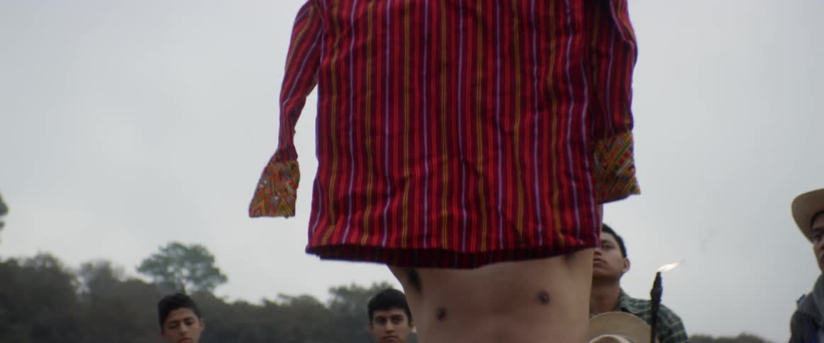 A shirtless man rising up his red shirt
