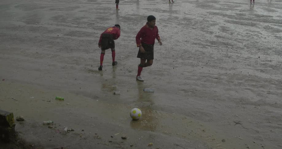 A group of men high five one another as they run across a wet muddy field