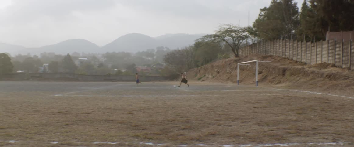 A group of people are playing soccer on an old field