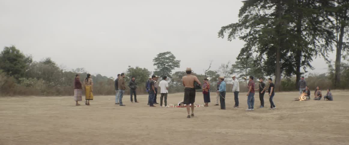 A man walks towards a group of people gathered in a circle out of doors