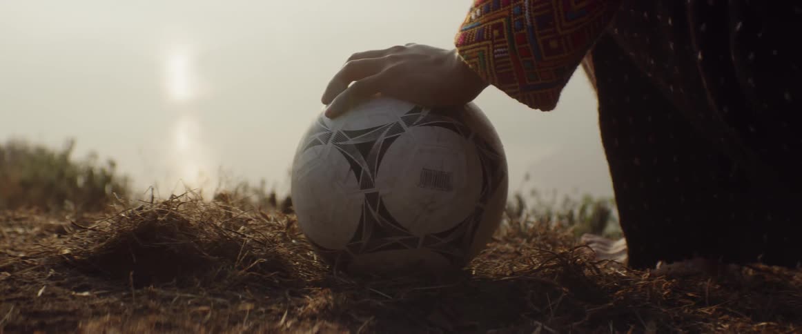 A child placed their hand atop a soccer ball